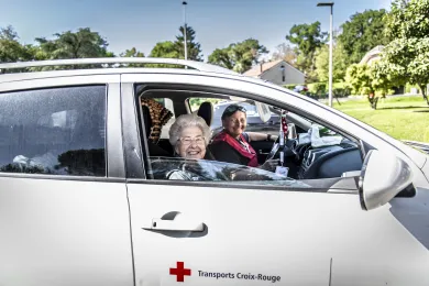 Une personne âgée est conduite par une bénévole Transports Croix-Rouge