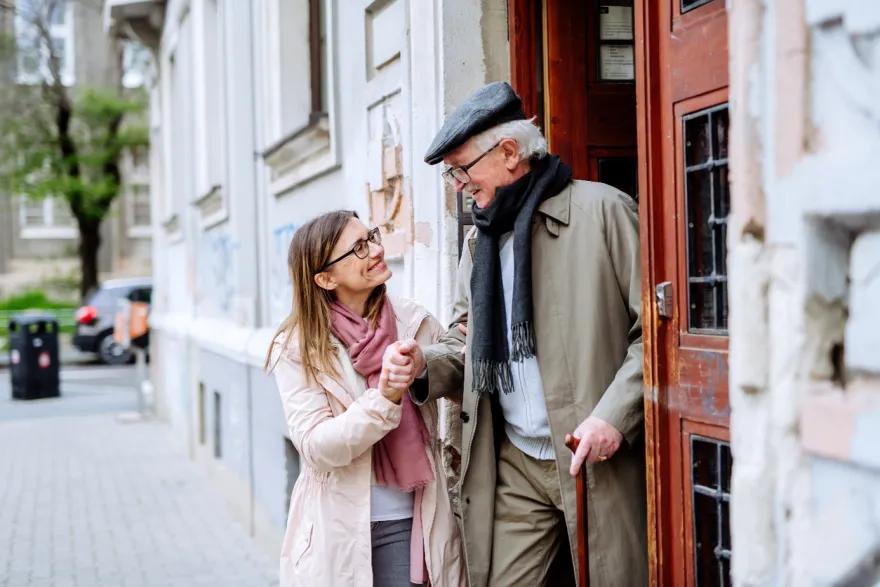 Une femme accompagne un senior à sortir de son domicile