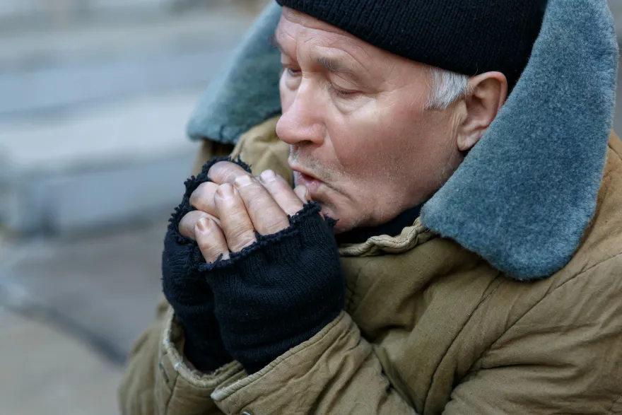 Personne sans abri qui a froid et essaye de réchauffer ses doigts