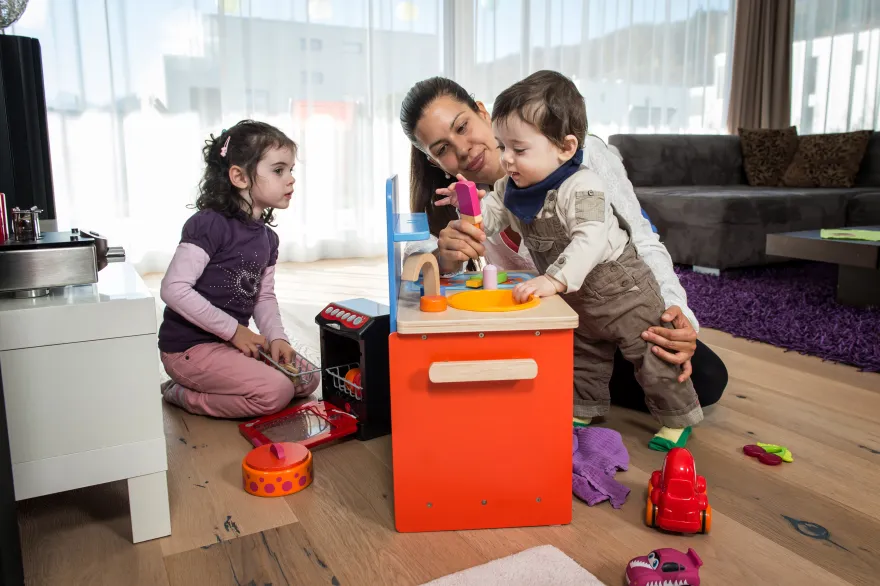 Femme, garde d'enfants à domicile, joue avec un petit garçon et une petite fille
