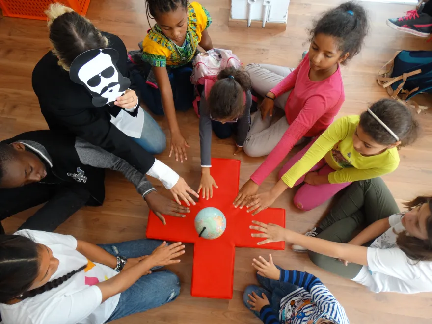 Un groupe d'enfants autour d'une croix-rouge en bois, symbole du Mouvement humanitaire